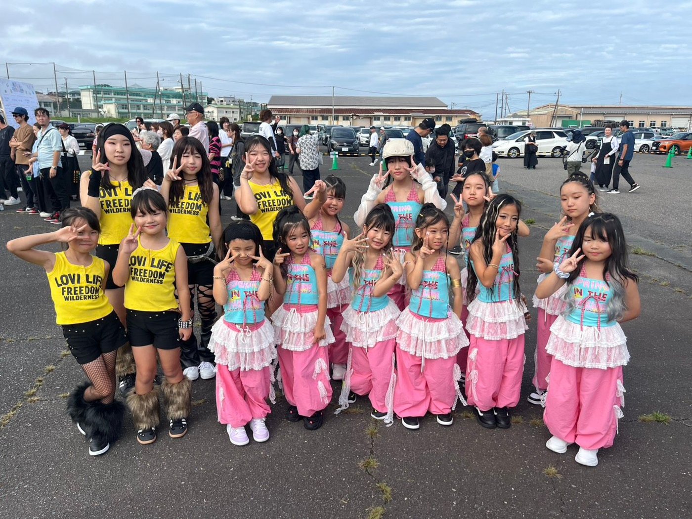 黄色のトップスとレースつきのピンクのパンツの衣装でそろえた2つのクラスの集合写真