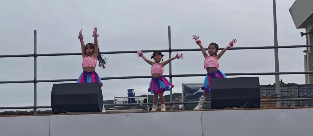 ステージで両手を高く上げて踊るリトルクラスの子どもたち